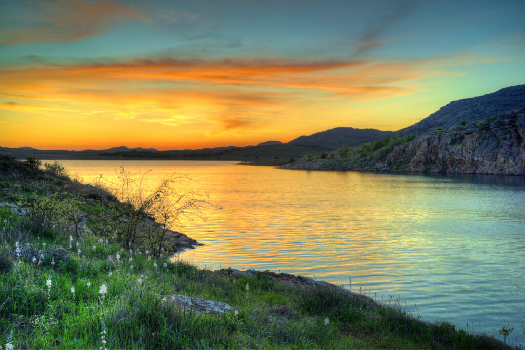 Golden sunset reflecting on Lake Elmer Thomas with Wichita Mountains visible.