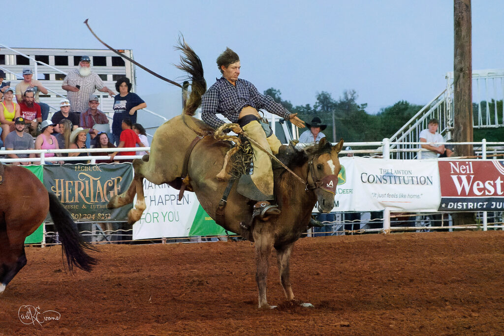 Cowboy riding bronc at rural Oklahoma rodeo event captures the spirit of perseverance.